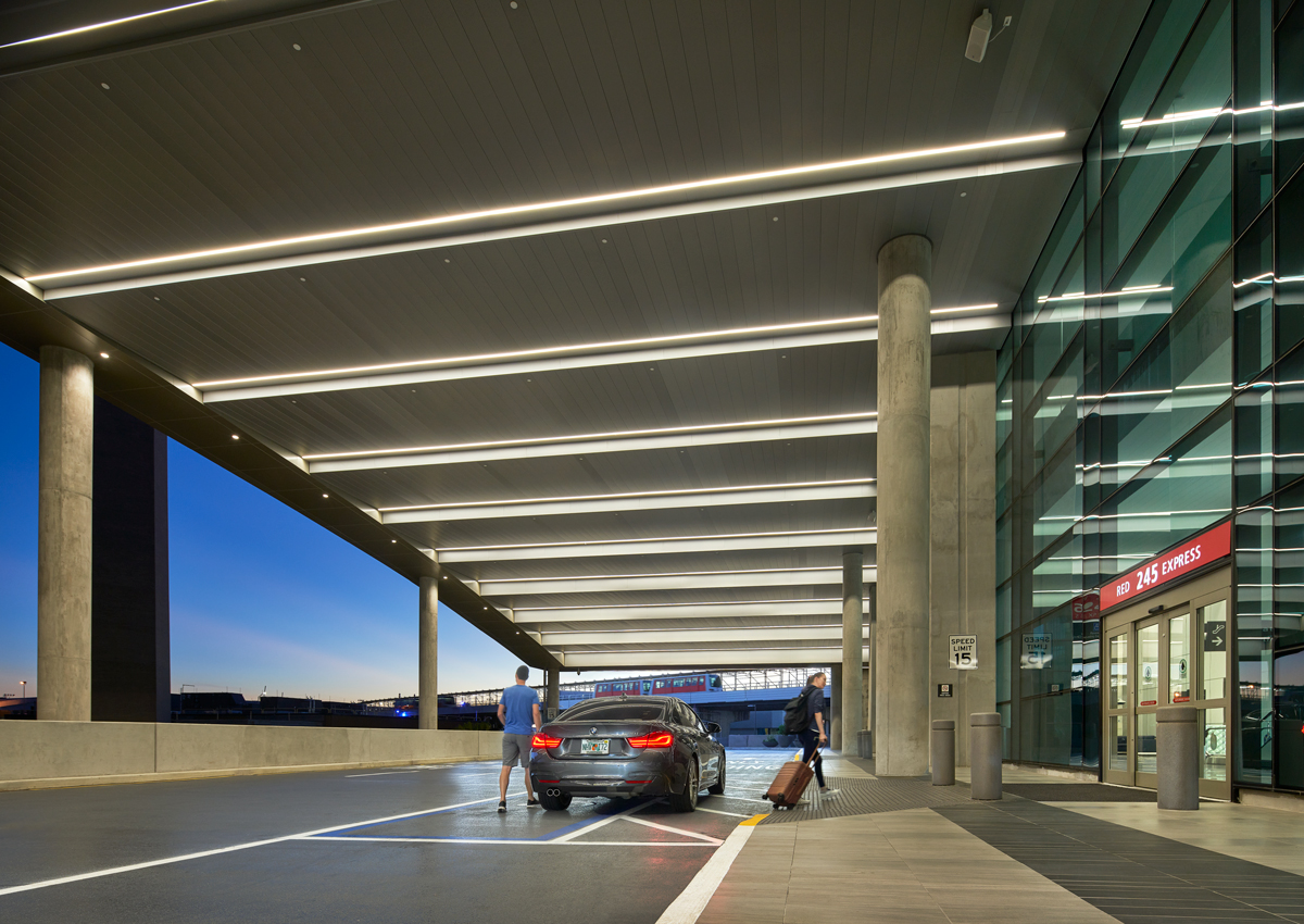 Red Express Curbsides entrance at Tampa International Airport, showing travelers unloading luggage beside a vehicle under a brightly lit canopy and glass façade with “Red Express” signage.