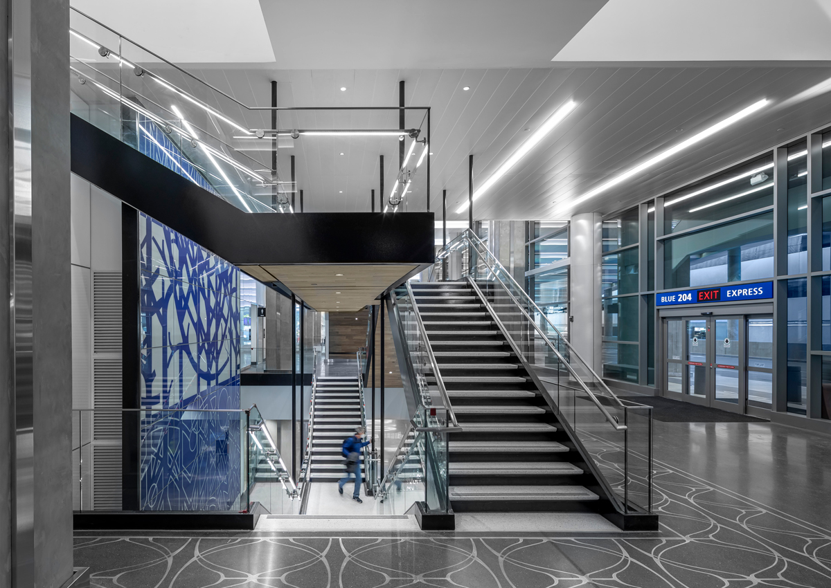 Interior view of Tampa International Airport’s Blue Express Curbsides showing stairways and open circulation space connecting curbside exits to the terminal.